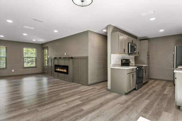 kitchen featuring light hardwood / wood-style flooring, stainless steel appliances, gray cabinetry, and light stone counters