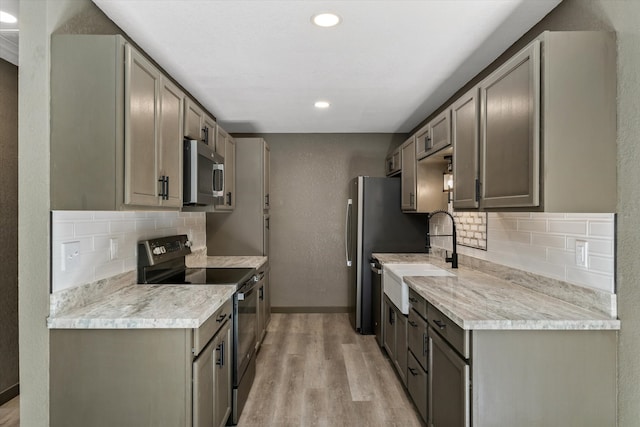 kitchen featuring decorative backsplash, light hardwood / wood-style floors, appliances with stainless steel finishes, and sink