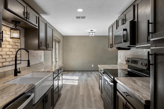 kitchen featuring appliances with stainless steel finishes, dark brown cabinetry, light hardwood / wood-style floors, and sink