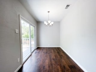 unfurnished dining area featuring an inviting chandelier and dark hardwood / wood-style floors