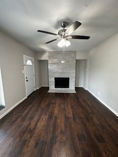 unfurnished living room with ceiling fan, a textured ceiling, a fireplace, and dark hardwood / wood-style flooring