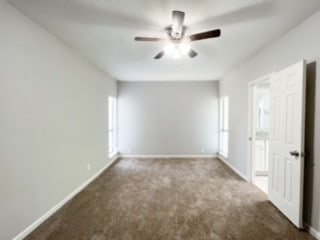 carpeted spare room featuring ceiling fan