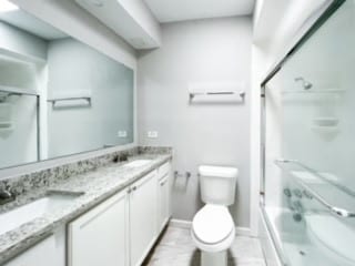 full bathroom featuring bath / shower combo with glass door, vanity, and toilet