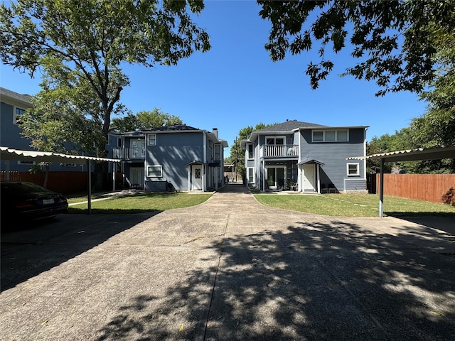 view of front of house with a balcony, a carport, and a front yard