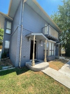 view of front of home featuring a balcony and a front lawn