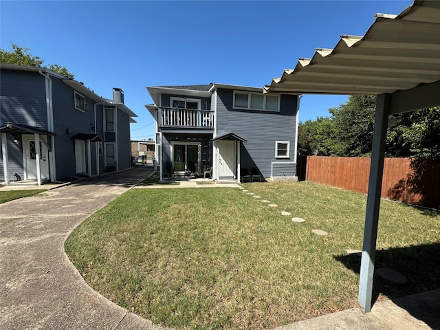 back of house with a balcony and a yard