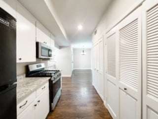 kitchen featuring appliances with stainless steel finishes, dark hardwood / wood-style floors, light stone counters, and white cabinets