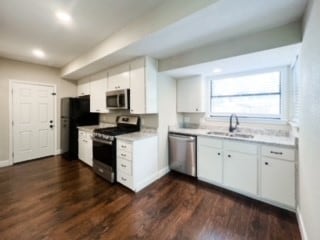 kitchen with dark hardwood / wood-style floors, sink, stainless steel appliances, and white cabinets