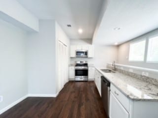 kitchen featuring light stone counters, dark hardwood / wood-style floors, sink, white cabinets, and stainless steel appliances