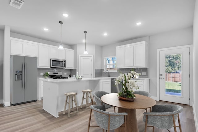 kitchen featuring a kitchen island, stainless steel appliances, hanging light fixtures, and a wealth of natural light