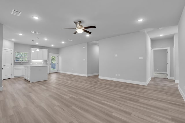 unfurnished living room featuring ceiling fan, sink, and light hardwood / wood-style floors