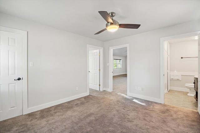 unfurnished bedroom with ceiling fan, a closet, connected bathroom, and light colored carpet