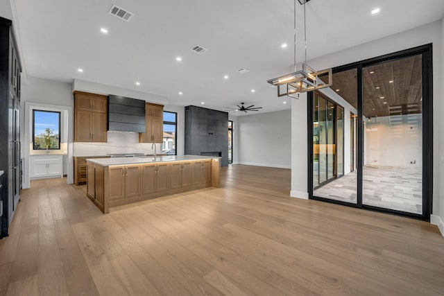 kitchen with ceiling fan, premium range hood, a spacious island, light hardwood / wood-style flooring, and hanging light fixtures