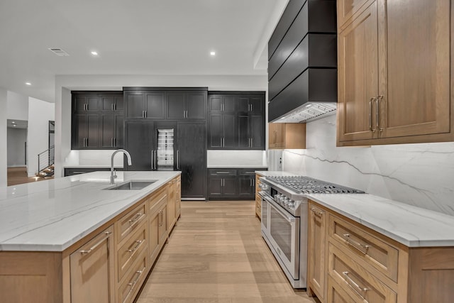 kitchen with light stone countertops, sink, custom range hood, and stainless steel stove