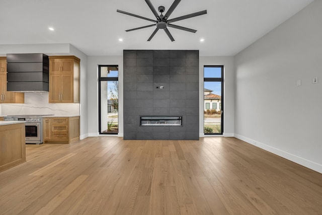 unfurnished living room featuring a fireplace, ceiling fan, plenty of natural light, and light hardwood / wood-style floors