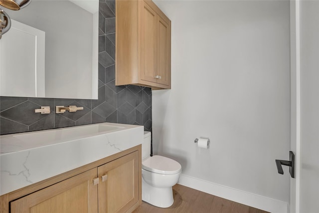 bathroom with wood-type flooring, toilet, vanity, and tasteful backsplash