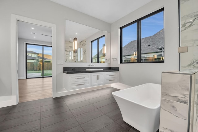 bathroom featuring tile patterned flooring, a tub to relax in, and vanity