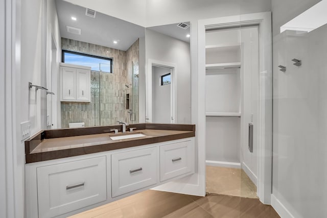 bathroom featuring tiled shower and vanity