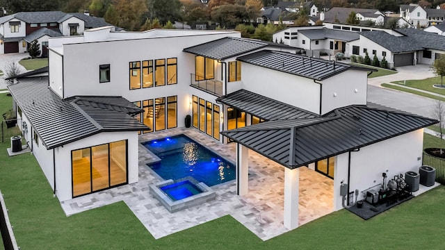 rear view of house featuring a lawn, a swimming pool with hot tub, cooling unit, and a patio area