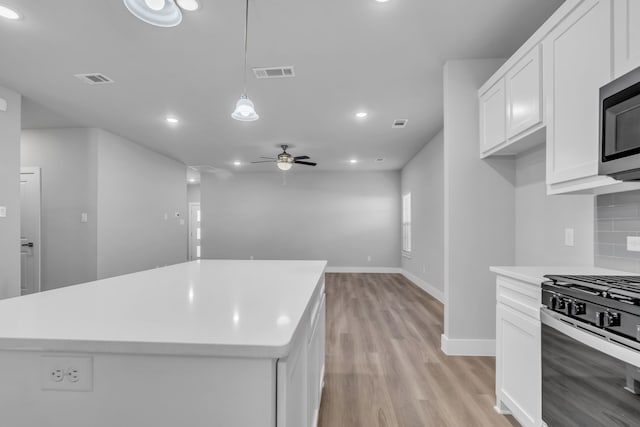 kitchen featuring white cabinets, hanging light fixtures, a kitchen island, and stainless steel appliances