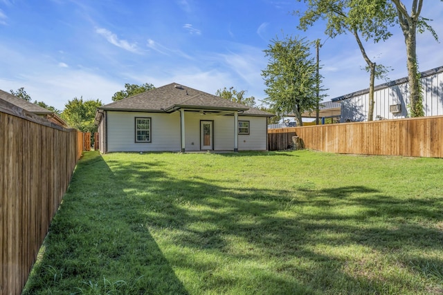 back of property with ceiling fan and a yard