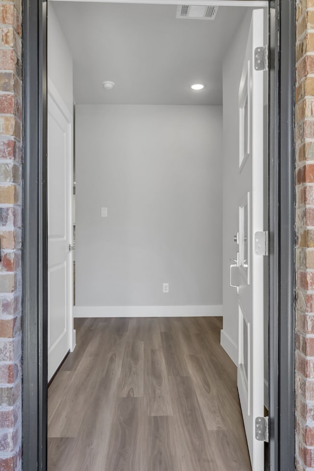 entryway featuring brick wall and hardwood / wood-style floors