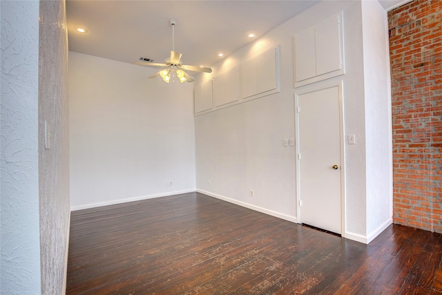 unfurnished room featuring ceiling fan, brick wall, and dark hardwood / wood-style flooring