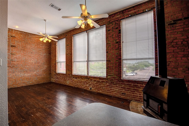 interior space featuring dark hardwood / wood-style flooring, ceiling fan, and brick wall