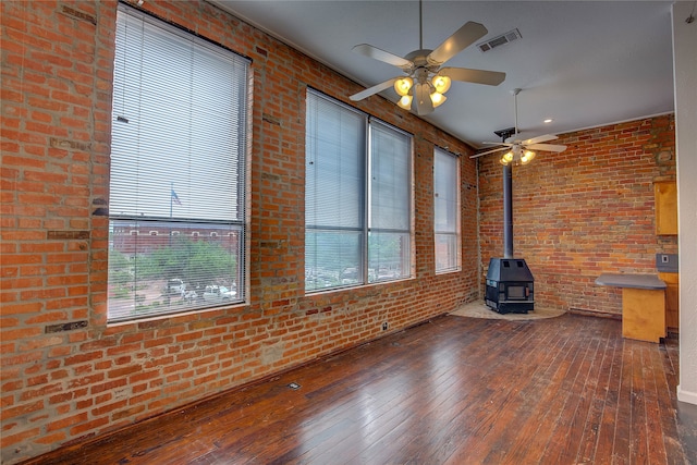 unfurnished living room with a wood stove, a wealth of natural light, and dark wood-type flooring