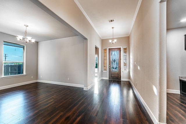 entrance foyer featuring dark wood-type flooring, crown molding, and a chandelier