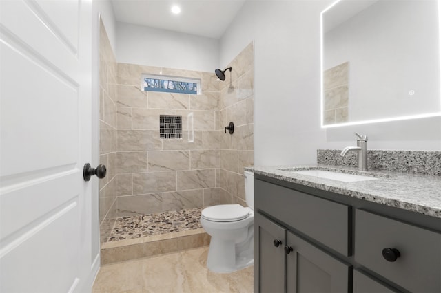 bathroom featuring tiled shower, vanity, and toilet