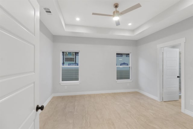 unfurnished room with ceiling fan and a raised ceiling