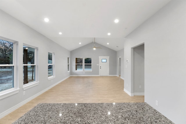 unfurnished living room featuring light hardwood / wood-style flooring, lofted ceiling, ceiling fan, and a healthy amount of sunlight