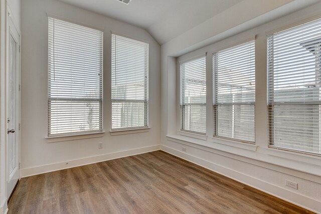 unfurnished room with hardwood / wood-style floors and vaulted ceiling