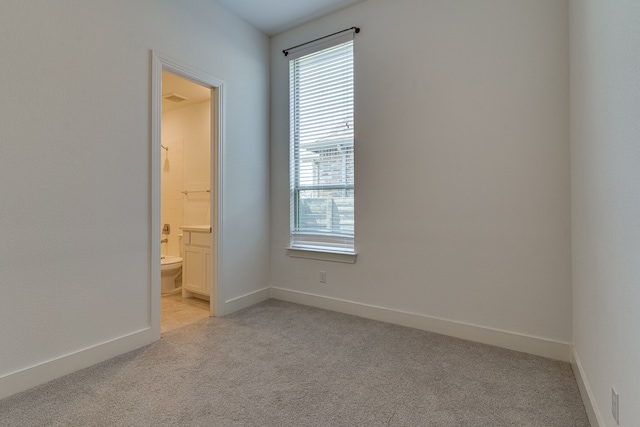 unfurnished bedroom with ensuite bathroom and light colored carpet