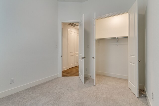 unfurnished bedroom with a closet and light carpet