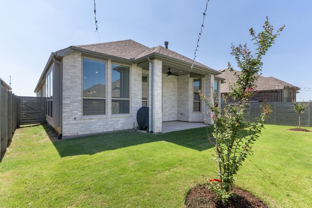 rear view of property with ceiling fan, a yard, and a patio area