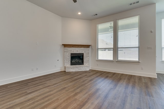 unfurnished living room featuring a brick fireplace, ceiling fan, and dark hardwood / wood-style flooring