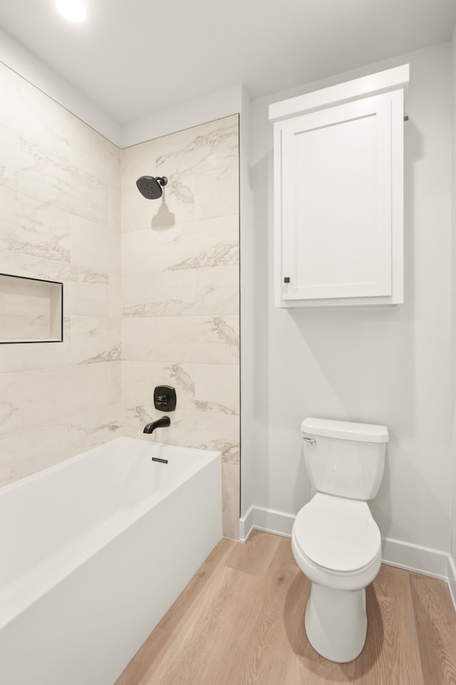 bathroom featuring wood-type flooring, toilet, and tiled shower / bath combo