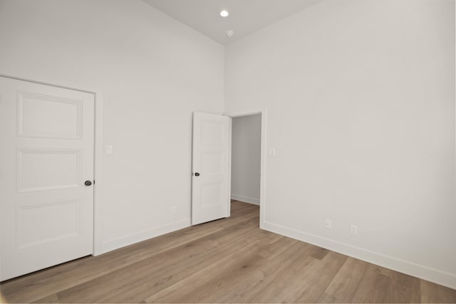 spare room with a towering ceiling and light hardwood / wood-style floors