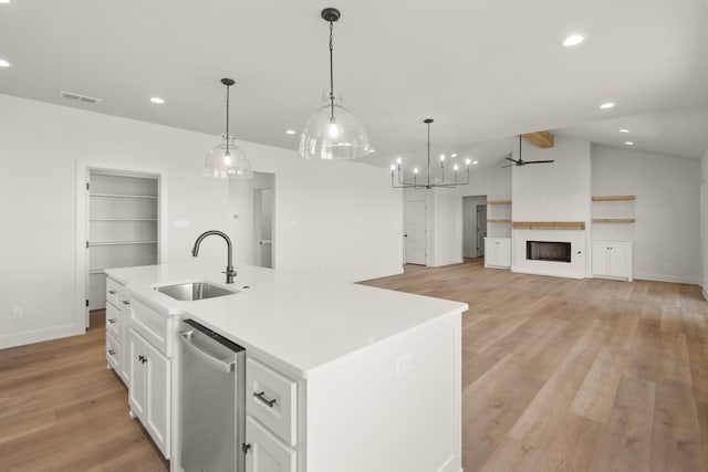 kitchen featuring decorative light fixtures, dishwasher, an island with sink, sink, and white cabinetry