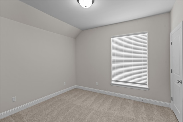 spare room with lofted ceiling and light carpet