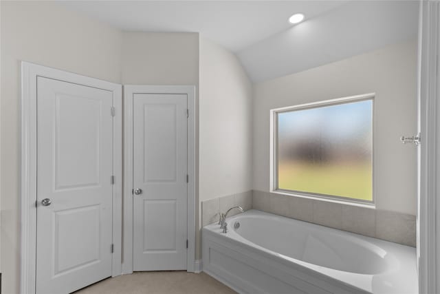 bathroom with tile patterned flooring, lofted ceiling, and a bathtub