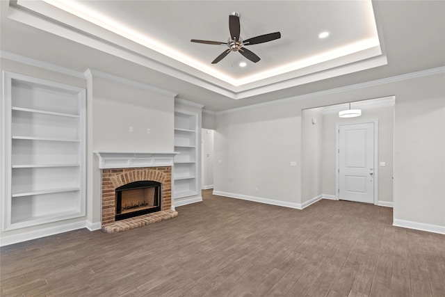 unfurnished living room with built in shelves, hardwood / wood-style floors, ceiling fan, and a brick fireplace