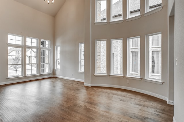 interior space featuring an inviting chandelier, a high ceiling, hardwood / wood-style floors, and plenty of natural light