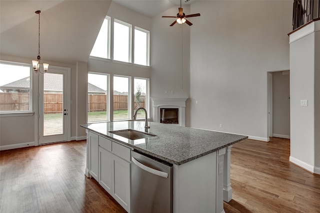 kitchen featuring white cabinets, light hardwood / wood-style flooring, stone counters, high vaulted ceiling, and dishwasher