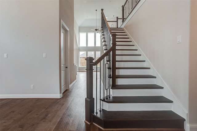 stairway featuring wood-type flooring, ceiling fan, and a high ceiling