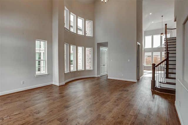 unfurnished living room with dark wood-type flooring, a chandelier, and a high ceiling