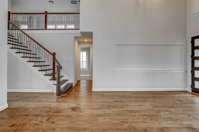 foyer entrance with a towering ceiling and light hardwood / wood-style flooring