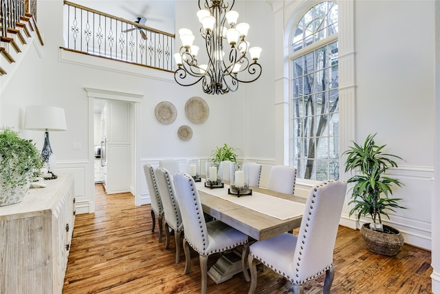 dining room with a notable chandelier, a towering ceiling, and hardwood / wood-style flooring